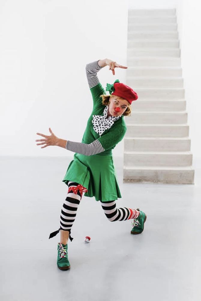 Clown Pip in groene jurk en gestreepte kousen maakt een vrolijk danspasje