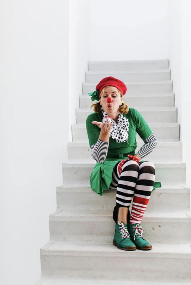 Clown Pip zit op een witte trap en geeft een kushandje