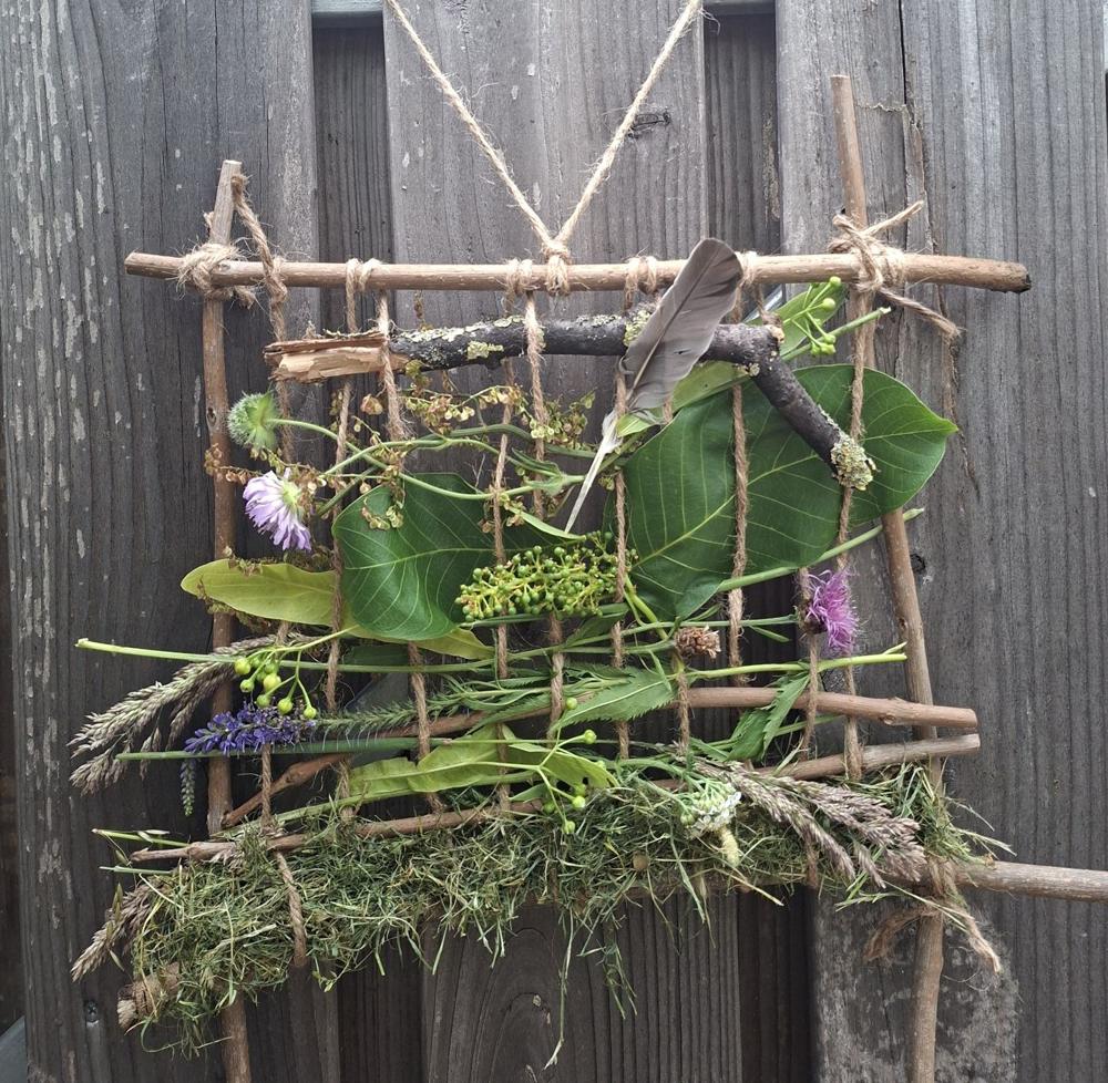 Een weefraam van takken, gevuld met bladeren, gras en bloemen